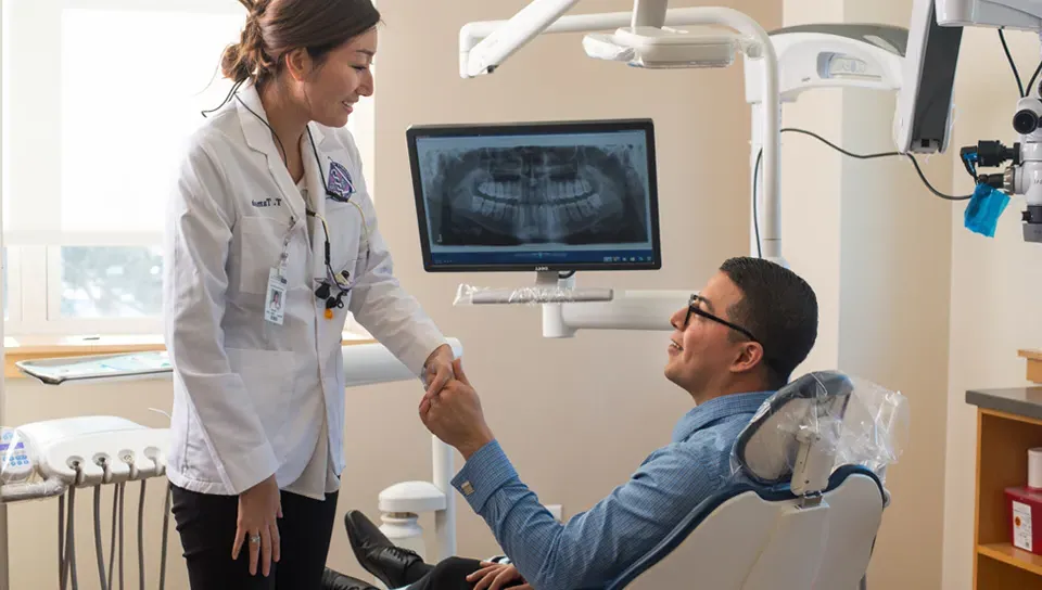 Female dental school student shakes hand with patient at UNE dental school's clinic in Portland, Maine.